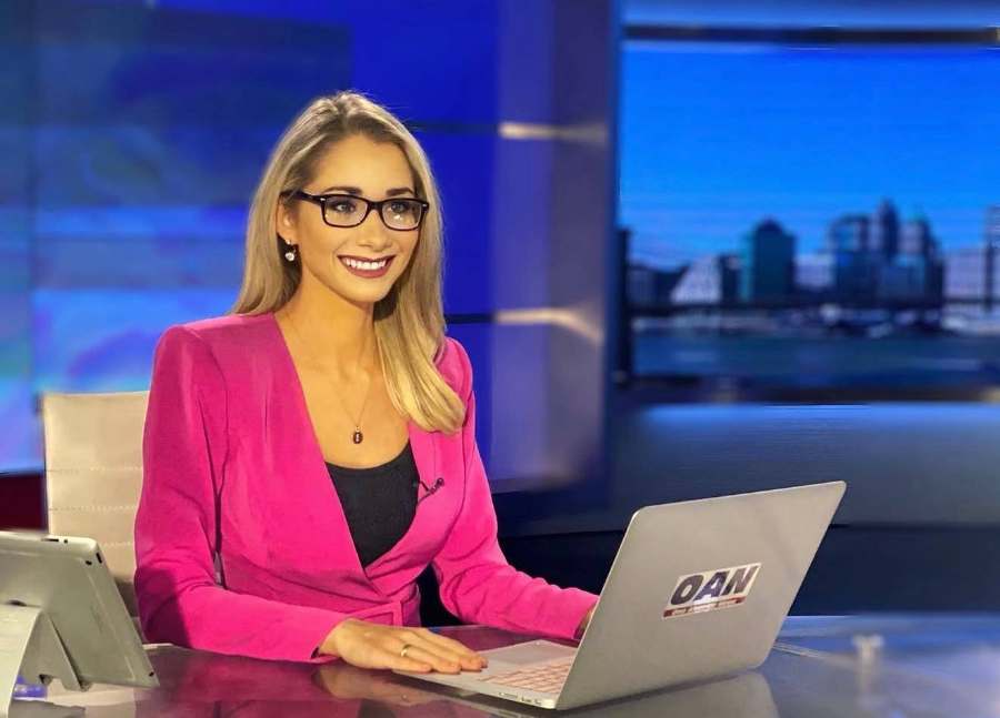 Emily at the OAN anchor desk with her laptop